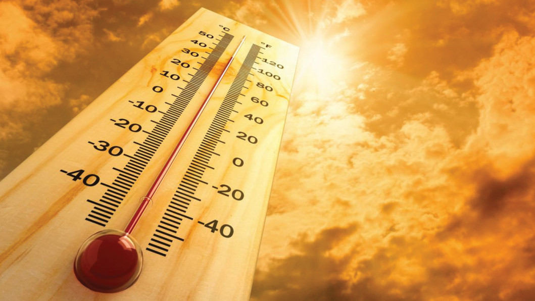A wooden thermometer reading close to 40 degrees Celsius against a blazing, sun-flared orange sky
